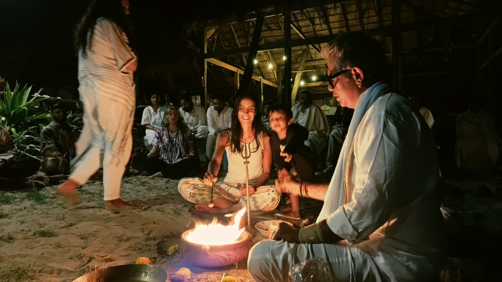 A fire ritual with participants gathered around the flame at a past Trika event