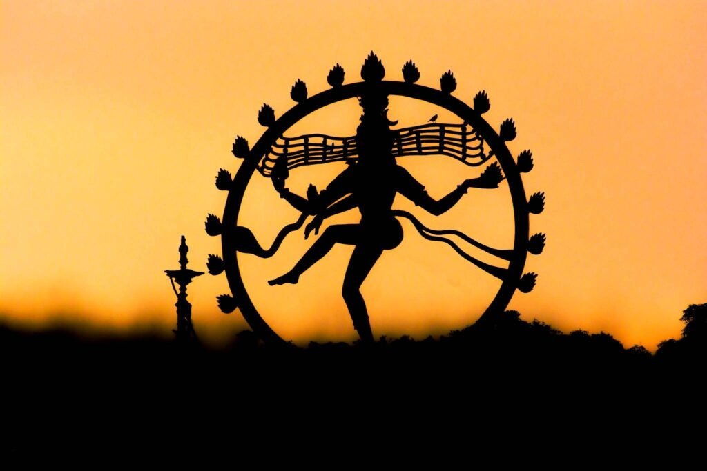 Nataraja, Shiva as the cosmic dancer, silhouetted against a golden sky