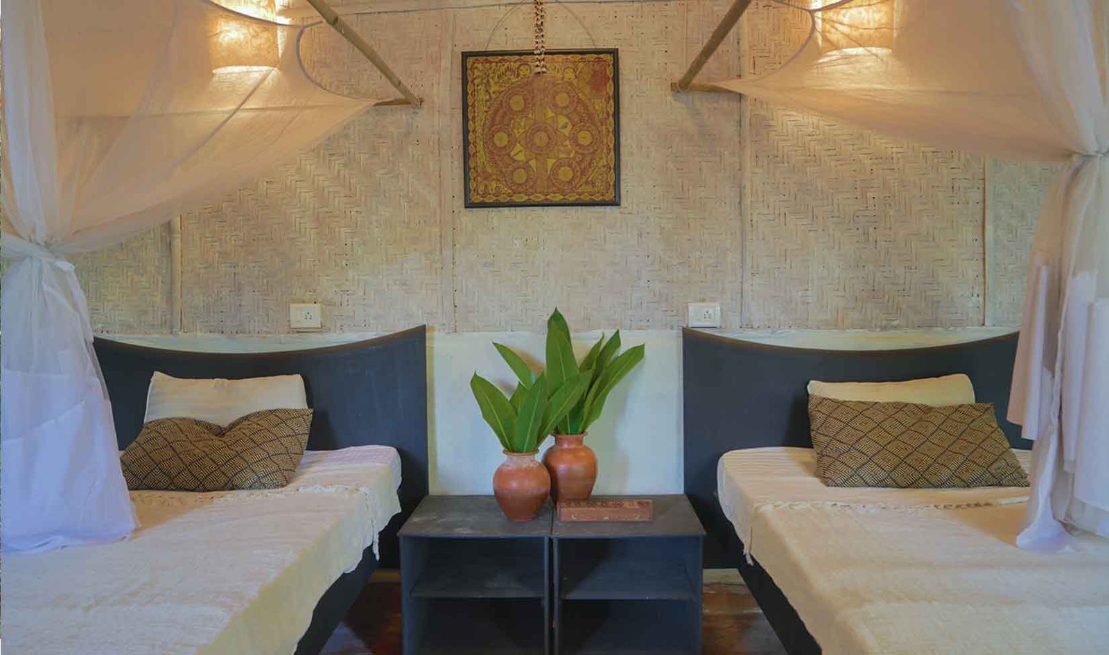 Twin beds with white mosquito nets in a SWAN cottage
