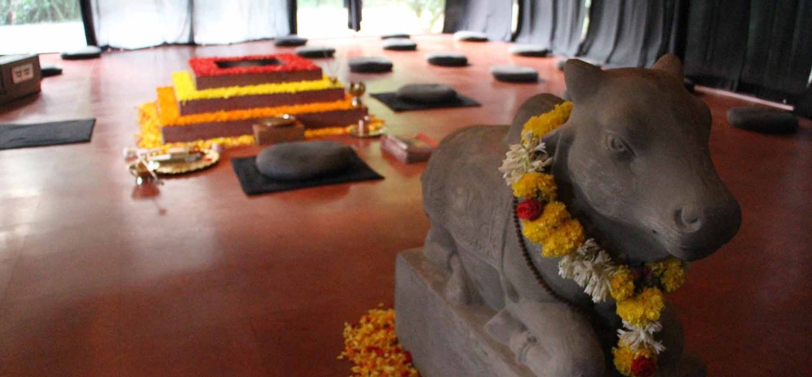 Inside SWAN’s fire temple, with a flower-decorated Nandi statue, Havan altar and meditation cushions